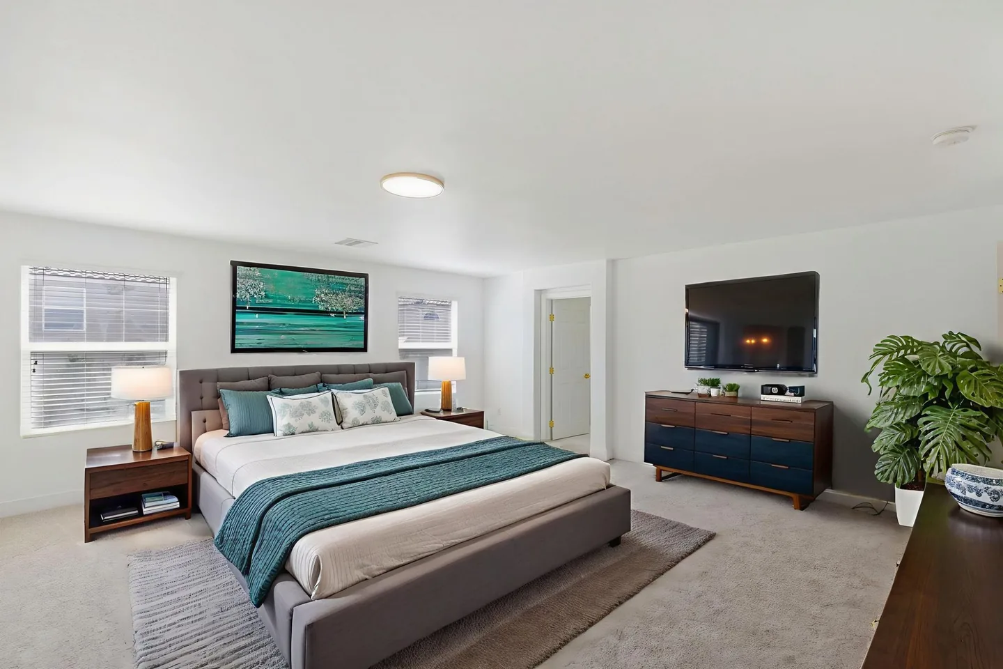 A furnished bedroom with light beige wall-to-wall carpet