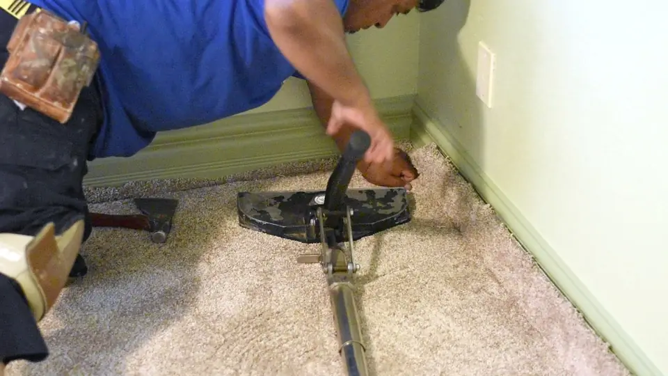 VFO installer stretching new carpet tight with a power stretcher