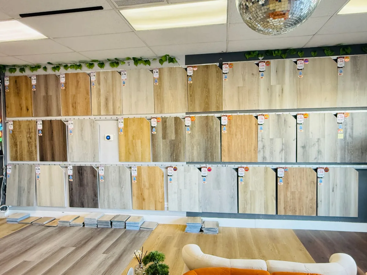 Three rows of vinyl plank sample boards on the wall of the Vegas Flooring Outlet showroom, with stacks of loose planks on the floor below