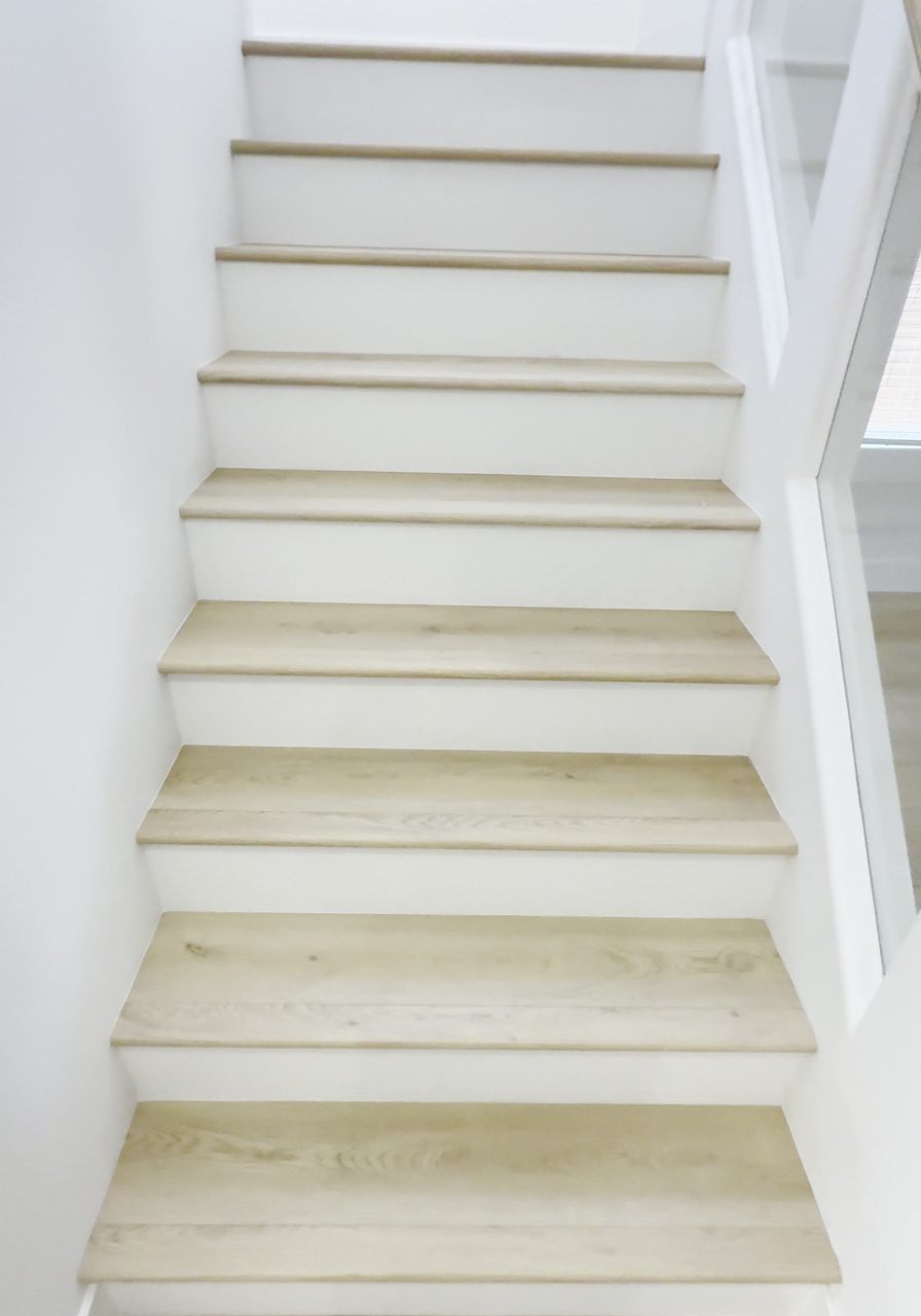 A finished staircase in a Las Vegas home with light wood-look treads, stair nosing on every step and white risers, installed by Vegas Flooring Outlet