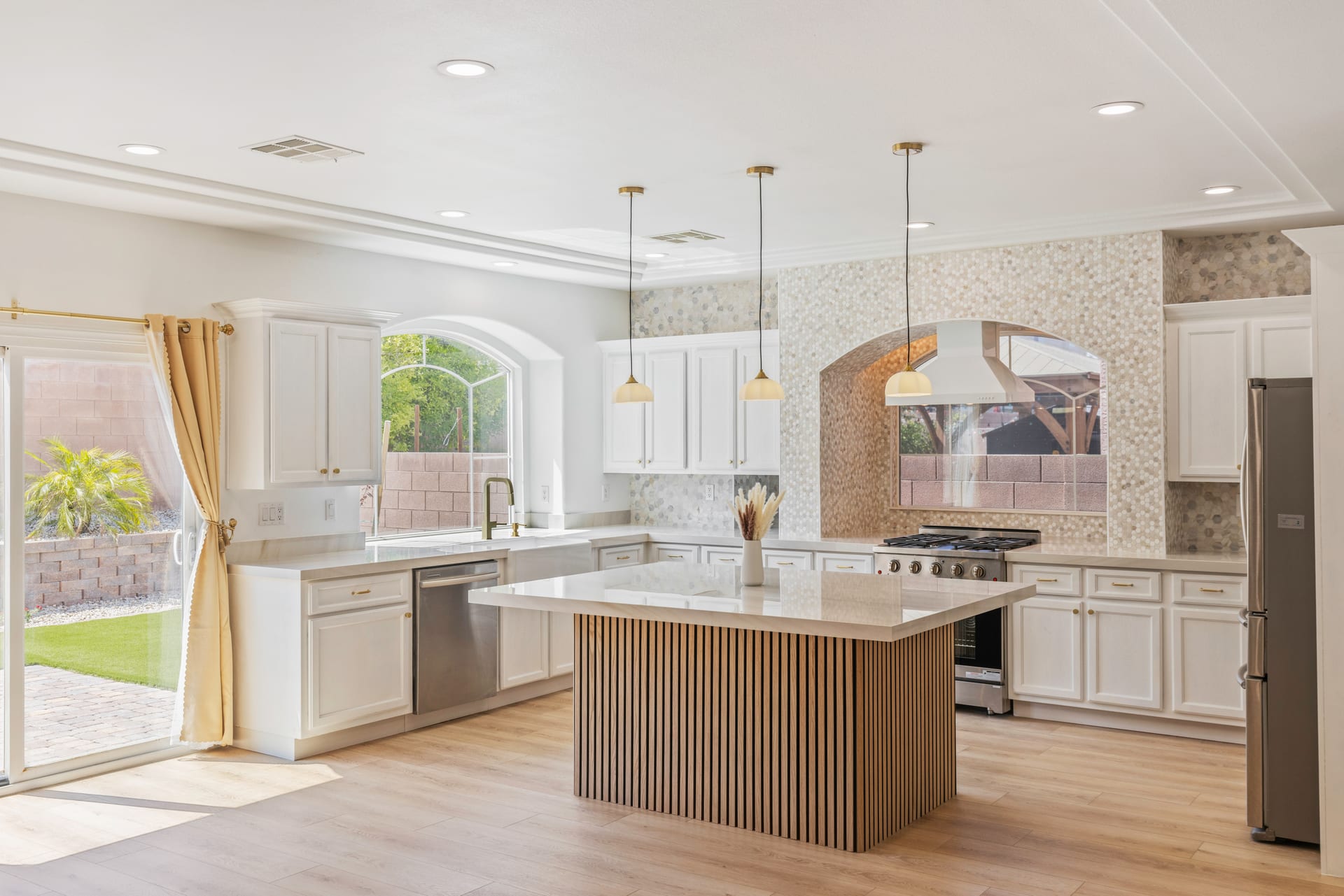Las Vegas kitchen with a mosaic tile backsplash, white cabinets and light plank flooring